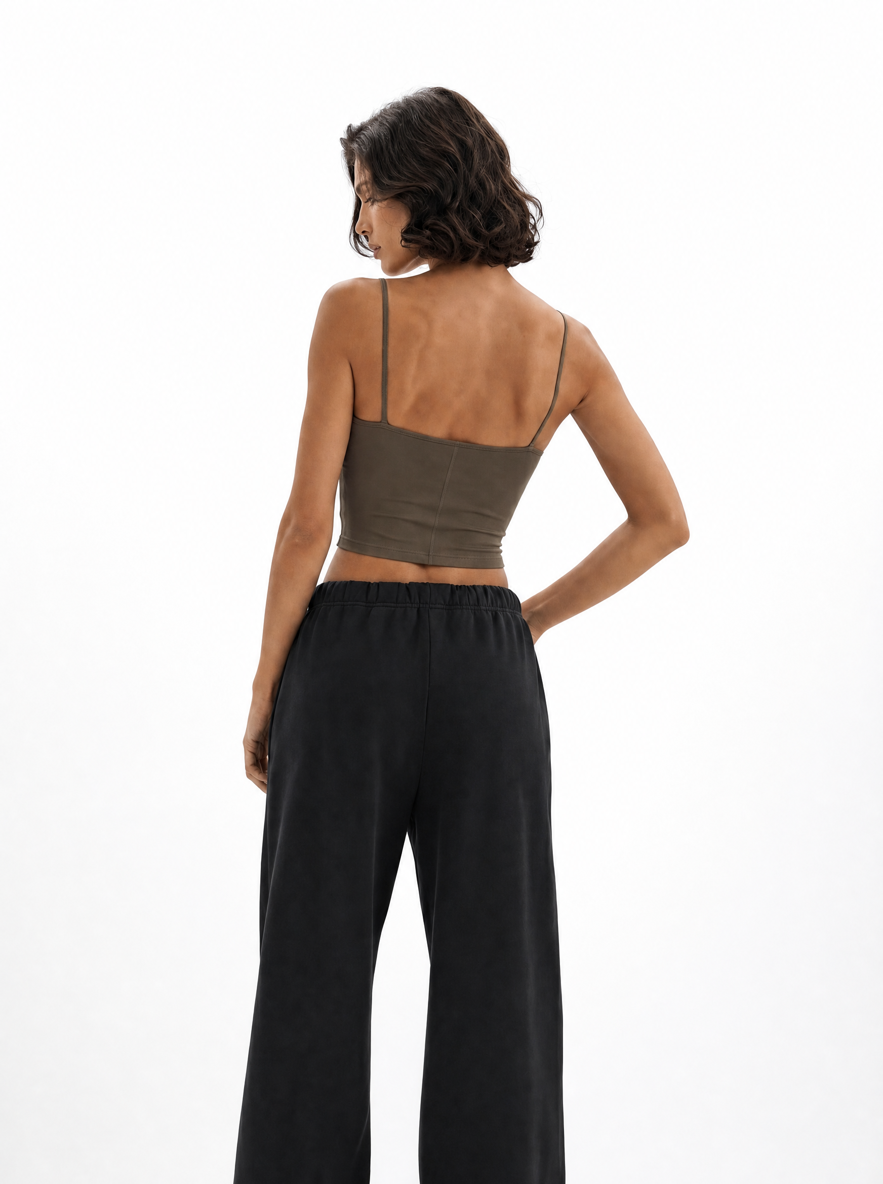 Woman wearing a green crop top and black pants on a white background